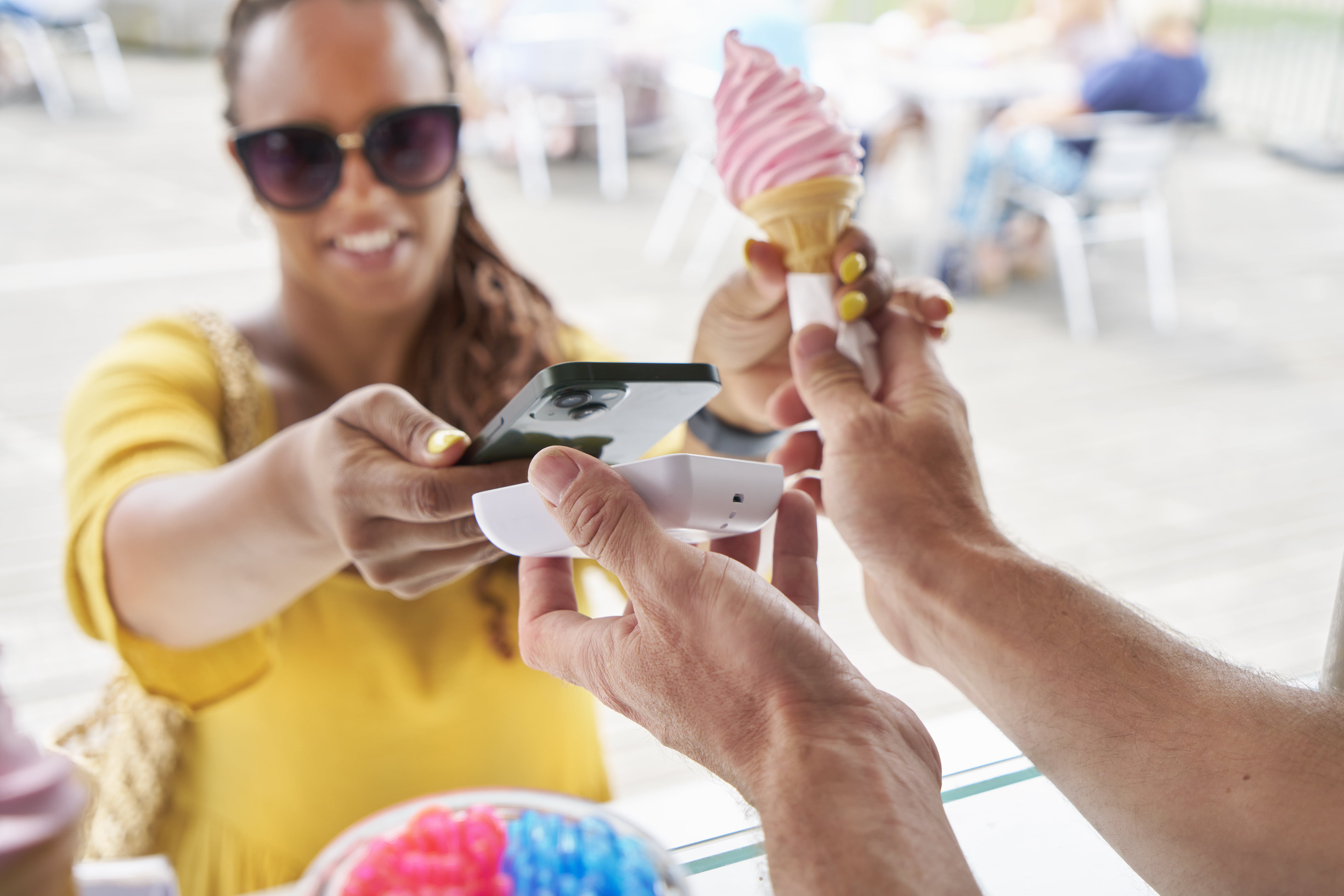 Person betaler for en is med mobil i en kortterminal i en iskiosk i utlandet.