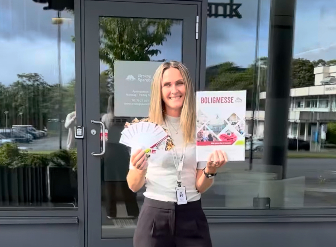 Annike som holder opp en plakat vedr. Boligmessen i Ålesund